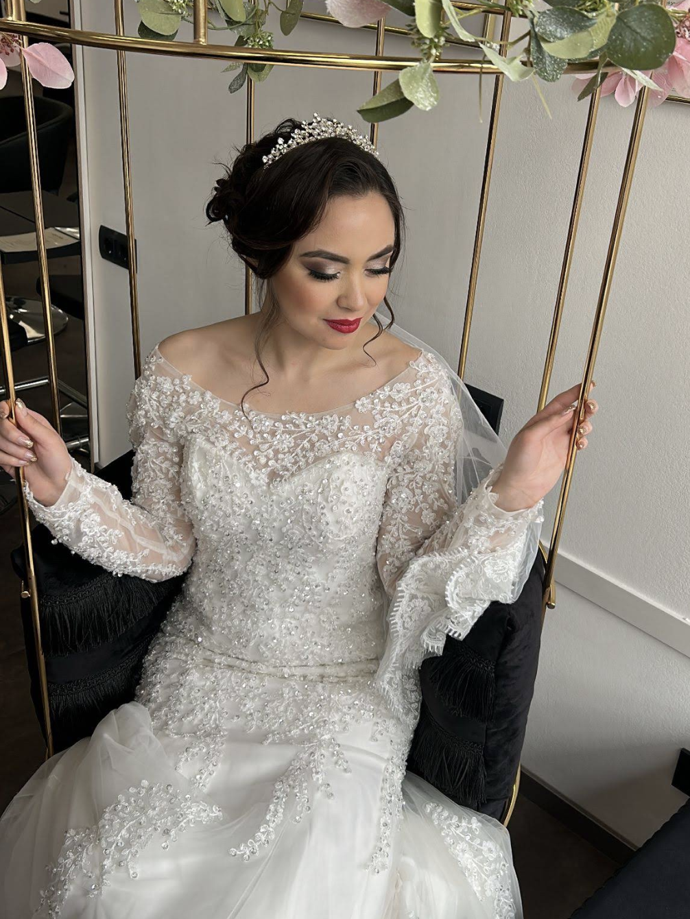 Braut mit hochgestecktem Haar, Diadem und Schleier sitzt im Salon von MadoFarah Beauty.